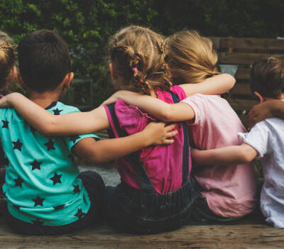 Group of kindergarten kids friends arm around sitting together